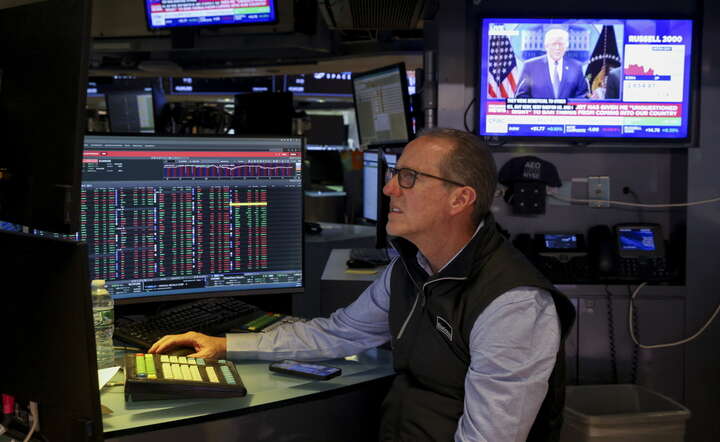 Makler na Wall Street. W tle relacja telewizyjna z konferencji prezydenta Donalda Trumpa po decyzji Sądu Najwyższego USA w sprawie ceł / autor: PAP/ EPA/SARAH YENESEL