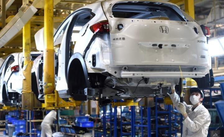Zamaskowany mężczyzna pracuje na linii montażowej w fabryce Hondy Dongfeng w Wuhan, prowincja Hubei, Chiny, 16 marca 2020 r.  / autor: PAP/EPA/SHEPHERD ZHOU