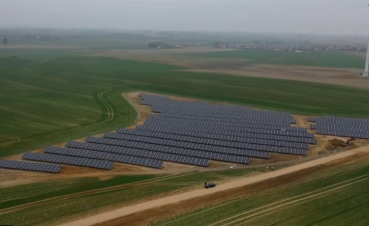 farma fotowoltaiczna budowana przez Energę, w tle turbina wiatrowa / autor: Energa