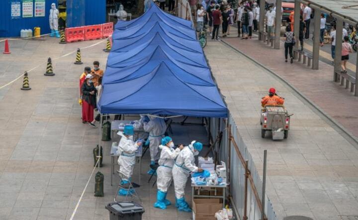 Pracownicy medyczni w pełnych kombinezonach przygotowują się do testowania ludzi na obecność Covid-19 w prowizorycznym centrum testowym koronawirusa w Pekinie. / autor: PAP/EPA/ROMAN PILIPEY